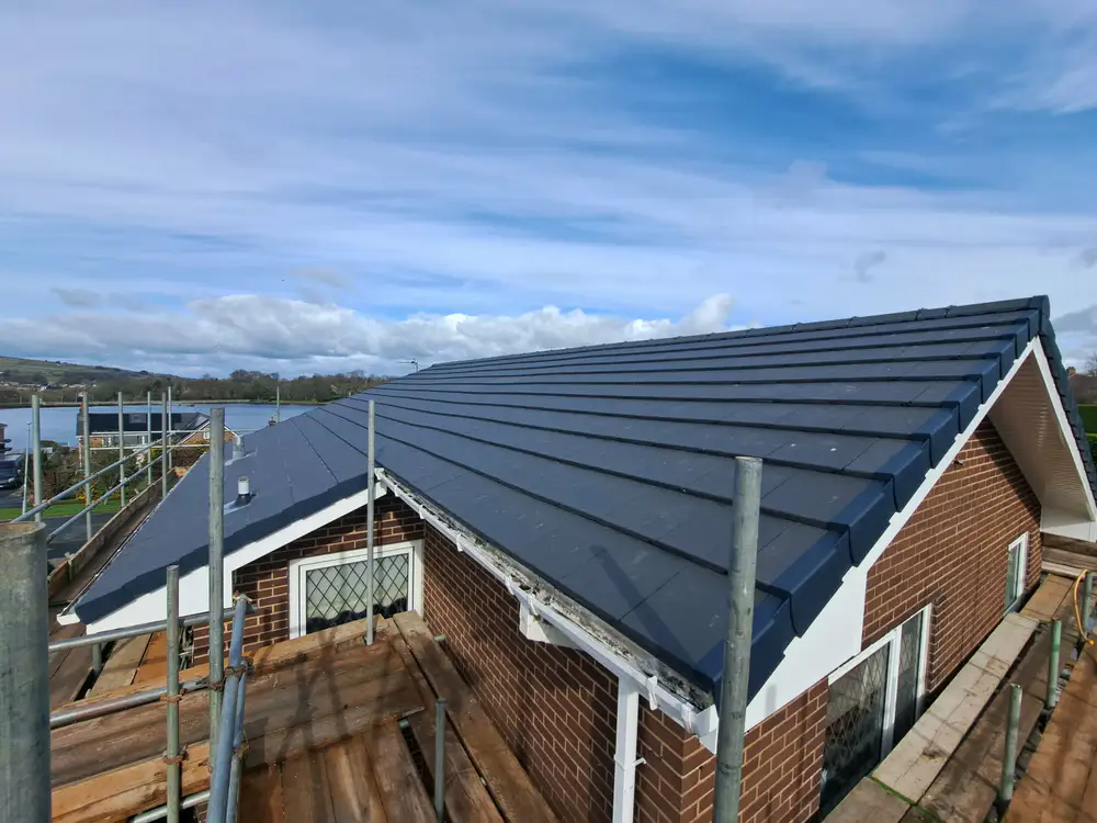 New grey tiled roof on a bungalow with scaffolding in place