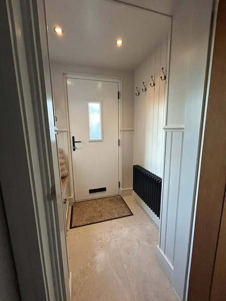 Finished hallway with a white entrance door and radiator